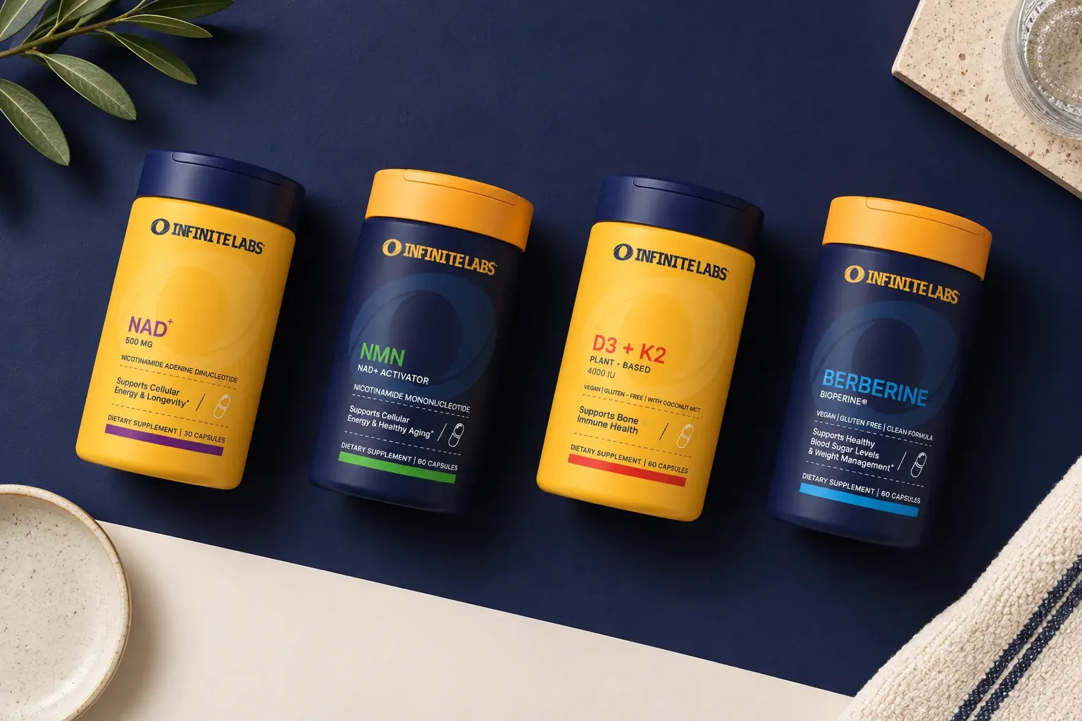An overhead arrangement of InfiniteLabs NAD+, NMN, D3 + K2, and Berberine bottles on navy.